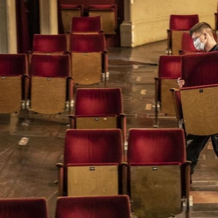 Ein Mann entfernt Stühle aus dem Zuschauerraum eines Theaters