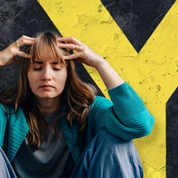 Eine sitzende Frau mit geschlossenen Augen rauft sich die Haare.