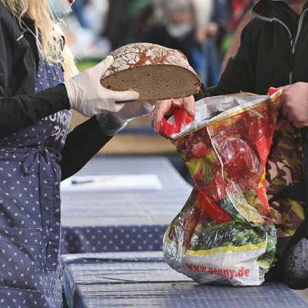 Bei der Tafel reicht eine Helferin Brot.