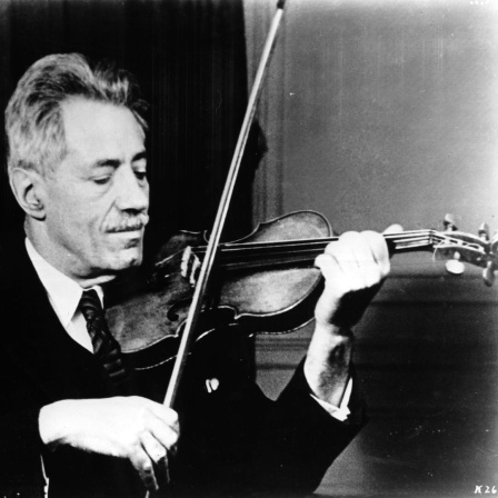 Die Schwarzweiß-Fotografie von ungefähr 1935 zeigt Fritz Kreisler in Anzug und Krawatte beim Spielen seiner Violine.