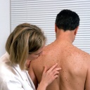 Eine Hautärztin untersucht den Rücken eines Patienten.