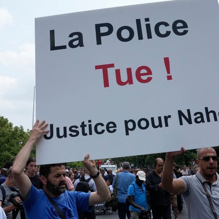 Demonstranten tragen ein Plakat mit der Aufschrift «Die Polizei tötet, Gerechtigkeit für Nahel» während eines Marsches für den getöteten 17-jährigen Nahel in dem Pariser Vorort Nanterre.