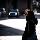 Eine Frau überquert bei windigem Wetter eine Straße in der Frankfurter Innenstadt. Sie wirkt allein und einsam.