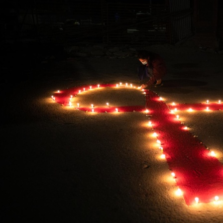 Viele Kerzen formen eine rote Schleife anlässlich des Welt-Aids-Tages