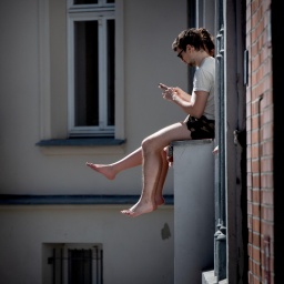 Junge Menschen lassen in Berlin ihre Beine aus dem Fenster baumeln. 