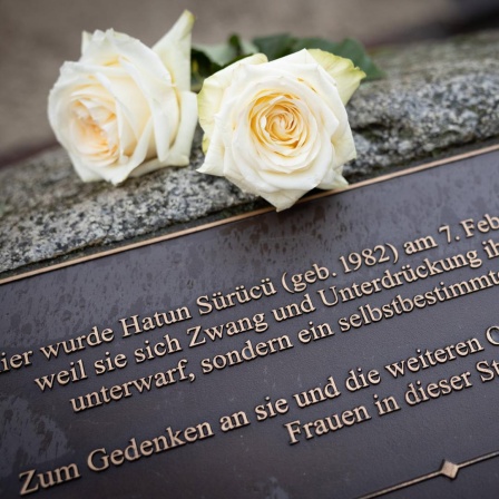Zwei weiße Rose liegen auf einem Gedenkstein, der am Tatort in der Oberlandstrasse in Tempelhof-Berlin an Hatün Sürücü erinnert.