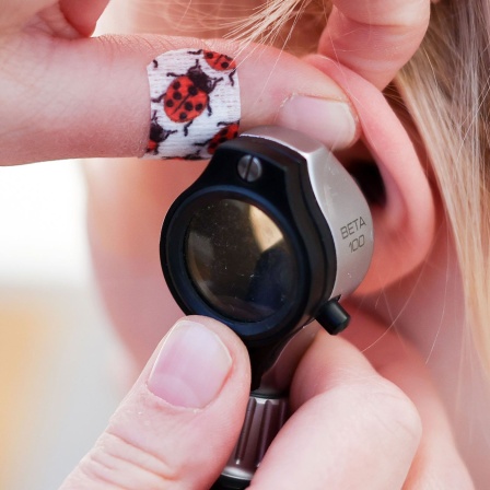 Mit einem Otoskop untersucht eine Kinderärztin ein Ohr eines Mädchens.