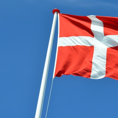 Die dänische Flagge vor blauem Himmel.