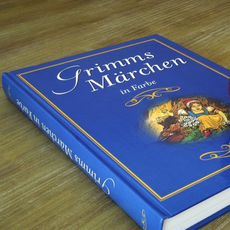 Ein Apfel liegt auf einem blauen Märchenbuch mit dem Namen "Grimms Märchen in Farbe".