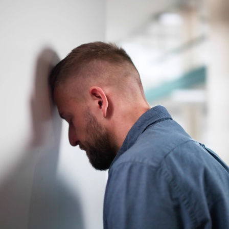 Ein Mann lehnt niedergeschlagen seinen Kopf an eine Wand.