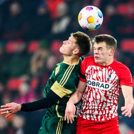 SC Freiburg - 1. FC Union Berlin, Union Berlins Kevin Behrens (l) in Aktion gegen Freiburgs Matthias Ginter