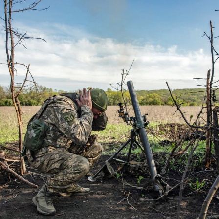 Ein Soldat einer Mörser-Einheit der ukrainischen Streitkräfte hält sich die Ohren zu, während er auf feindliche Stellungen in den Vororten der Stadt Bachmut im Gebiet Donezk im Osten der Ukraine feuert.