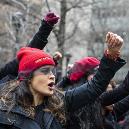 Frauen protestieren und singen, mit erhobenen Fäusten, vor dem Gerichtsgebäude