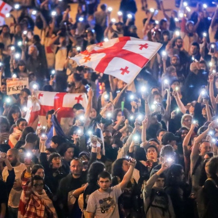 Georgien, Tiflis: Demonstranten schwenken georgische Nationalfahnen während einer Protestaktion der Opposition