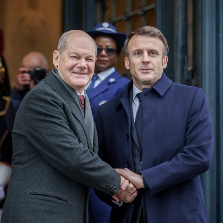 Bundeskanzler Olaf Scholz (SPD, l), wird von Emmanuel Macron, Präsident von Frankreich, zu der Festveranstaltung zum 60. Jubiläums des Élysée-Vertrags im Rahmen des Deutsch-Französischen Ministerrats begrüßt. 