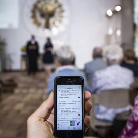 Bei einem Gottesdienst im Rahmen des "Sublan"-Projektes im Juli 2017 in Hessen können sich die Besucher per Smartphone und Tablet-Computer direkt in die Predigt und die Fürbitte-Gebete einschalten. Im Vordergrund hält eine Person ein Smartphone, im Hin