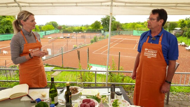 &#034;Rezeptsucherin&#034; Susanne Nett und Matthias Fahrnschon am Kochen im Freien, im Hintergrund ein Tennisplatz