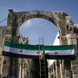 Ein Arbeiter hängt eine Flagge der syrischen Revolutionäre - grün, weiß, schwarz mit roten Sternen am Eingang zu dem Suq al-Hamidiya, vor dem Freitagsgebet auf.