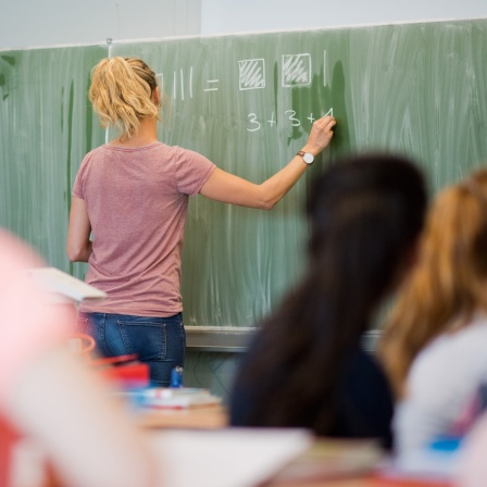 Junge Lehrerin schreibt 2016 an eine Schultafel. 