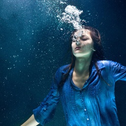 Eine Frau atmet unter Wasser aus