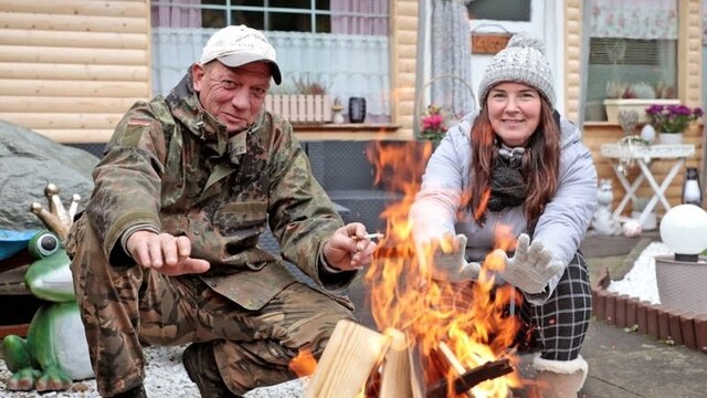 Sonja und Thomas Schmidt wärmen sich die Hände an einem Feuer