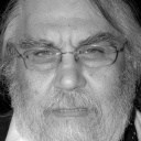 Ein älterer Mann mit grauen langen Haaren, Vollbart und Brille schaut kritisch in die Kamera