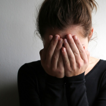 Eine junge Frau schlägt die Hände vor das Gesicht