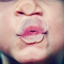 Ein Kind drückt Nase und Mund wie bei einem Kuss gegen eine Glasscheibe.