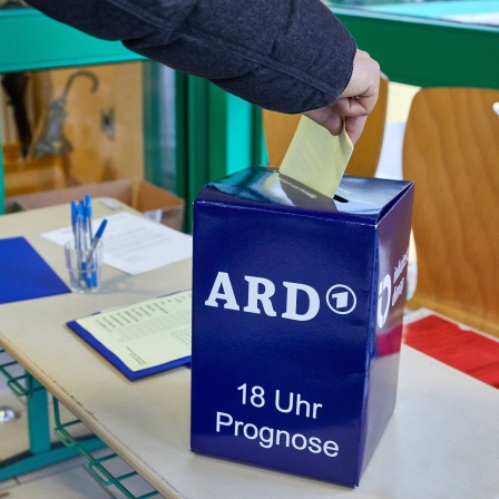 Ein Wähler steckt einen Fragebogen in eine zusätzliche «Wahlurne» der Infratest dimap für die Wahlprognose der ARD zur Bürgerschaftswahl im Eingangsbereich eines Wahllokals in Hamburg-Lurup.