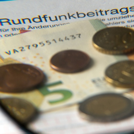 Auf einem Tisch in einem Büro in Dresden (Sachsen) liegt am 15.04.2016 Münzgeld auf Formularen für Bürgerinnen und Bürger zu den Rundfunkbeiträgen.