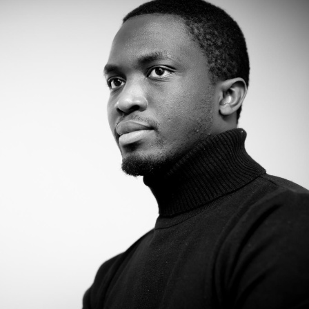 Der senegalesische Autor Mohamed Mbougar Sarr. Es handelt sich um ein Schwarzweiß-Foto, der Autor trägt einen dunklen Rollkragenpullover.