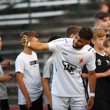  Der Fussballer Nader El-Jindaoui umringt von Fans, die ein Selfie mit ihm wollen, Berlin 2022.