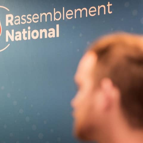 Ein unscharfer männlicher Kopf steht vor einem Plakat, Rassenblément National.