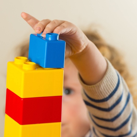 Kleinkind baut Turm mit Legosteinen