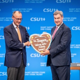 Auf dem CSU-Parteitag 2023 in München übergibt Markus Söder Friedrich Merz ein Lebkuchenherz mit der Aufschrift "In Bayern lebt es sich einfach besser!".