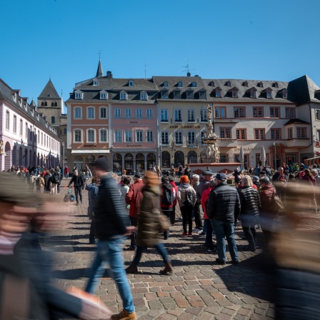 Menschen stehen am Petrusbrunnen auf dem Hauptmarkt in der Trierer Innenstadt