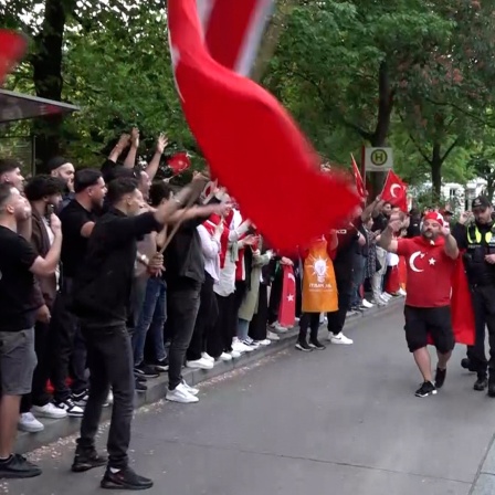 Zahlreiche Menschen feiern in Hamburg den Ausgang der Wahlen in der Türkei. Einige halten eine große türkische Fahne.