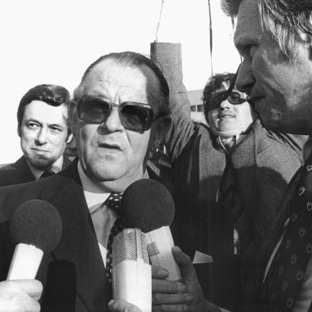 Staatsminister Hans-Jürgen Wischnewski (Mitte) wird nach der Rückkehr aus Mogadischu am 18. Oktober 1977 auf dem Köln-Bonner Flughafen von Ernst-Dieter Lueg von der ARD befragt. Hinten links der Regierungssprecher, Staatssekretär Klaus Bölling.