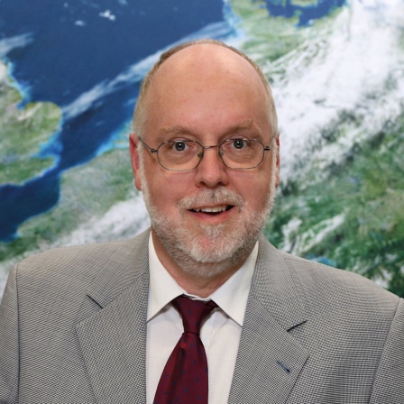 Prof. Roland Potthast, Direktor des Niederstwertprinzip (NWP) beim Deutschen Wetterdienst, steht vor einer Wetterkarte. Kann KI die zunehmenden Extremwetter richtig vorhersagen? Menschliche Kontrolle ist besser, sagt Prof. Roland Potthast. Er ist zu Gast in SWR1 Leute.