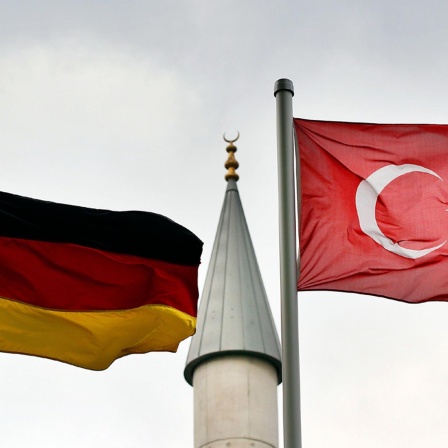 Eine deutsche und eine türkische Fahne wehen vor dem Minarett der Merkez-Moschee in Duisburg.