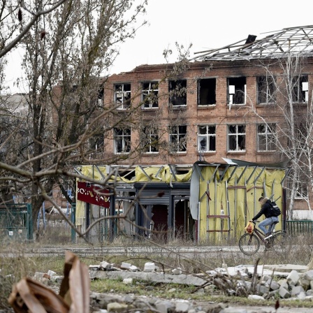 Ukraine, Isjum: Ein Mann fährt mit dem Fahrrad an einem durch Beschuss zerstörten Gebäude vorbei, nach Abzug russischer Truppen aus der Region.