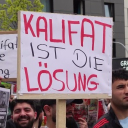 Nahaufnahme von einem Schild, das auf einer Demo hochgehalten wird. Darauf steht "Kalifat ist die Lsöung".