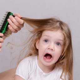 Junges Mädchen mit langen Haaren bekommt von einer Frau die Haare gebürstet