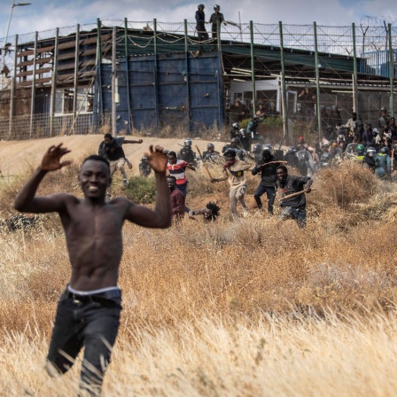 Migranten rennen auf spanischen Boden, nachdem sie die europäischen Grenzanlagen überwunden haben, die die spanische Enklave Melilla von Marokko trennen (Bild: dpa / Javier Bernardo)