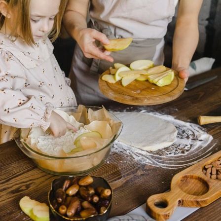 Tochter und Mutter backen gemeinsam einen Apfelkuchen.