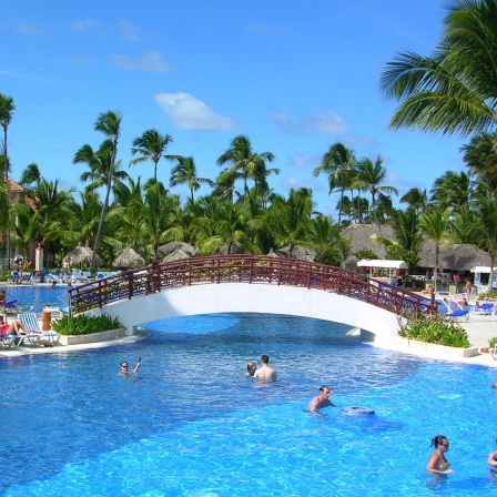 Hotelgäste entspannen im Pool einer Ferienanlage.