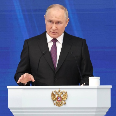 Der russische Präsident Putin steht bei einer Rede an einem weißen Stehpult
