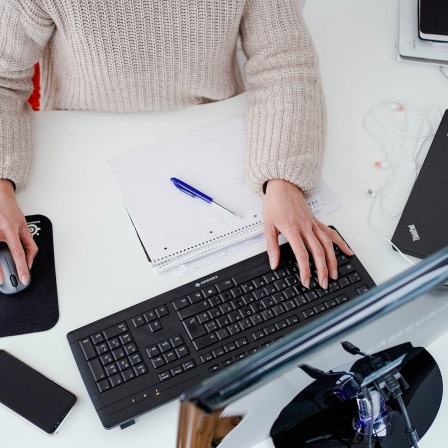 Eine Frau sitzt am Schreibtisch und arbeitet am Computer