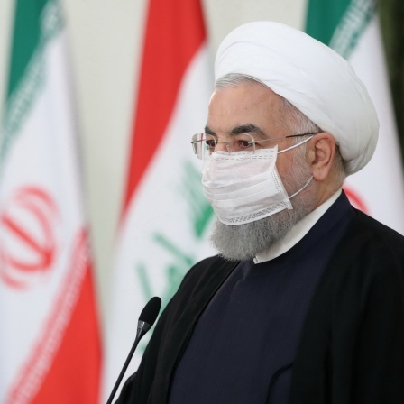Hassan Ruhani bei einer Pressekonferenz vor iranischen Flaggen