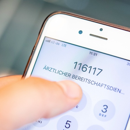 Mann wählt Notrufnummer 116 117, des Ärztlichen Bereitschaftsdienstes auf einem Smartphone.